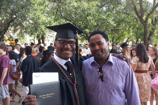 Student poses with father at college graduation.