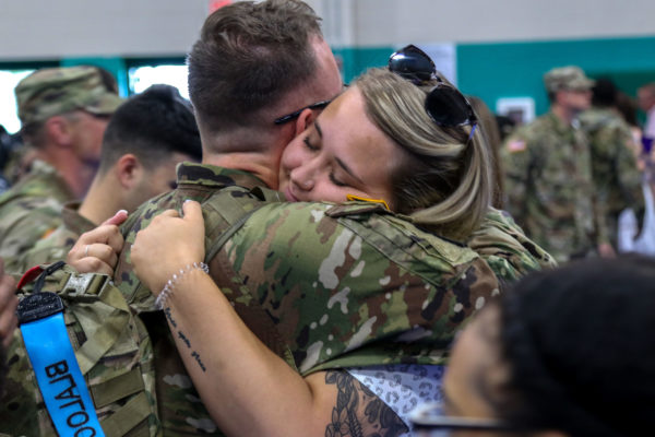 A soldier hugs a woman.