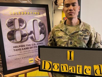 Soldier poses with a donation sign