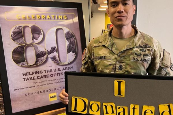 Soldier poses with a donation sign