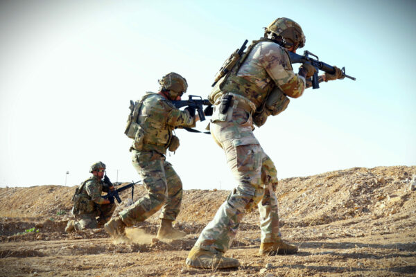 Three U.S. Army Soldiers in uniforms point weapons.