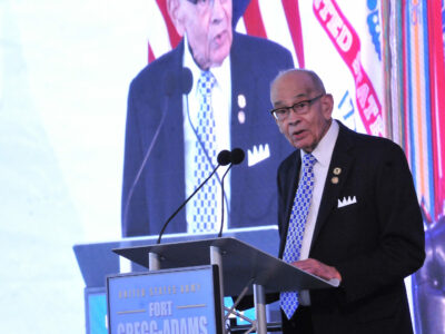 A man in a suit stands at a podium and talks into a microphone.
