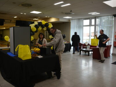 People stand at a table adorned in black and yellow decorations.