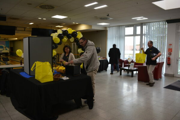 People stand at a table adorned in black and yellow decorations.