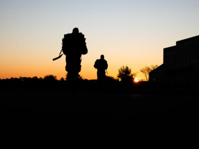 Two U.S. Soldiers are silhouetted at dawn.