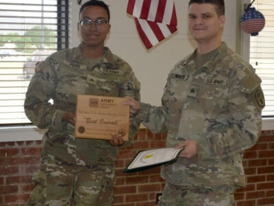 Two U.S. Soldiers in uniform pose for a photo whilst holding a plaque and certificate.